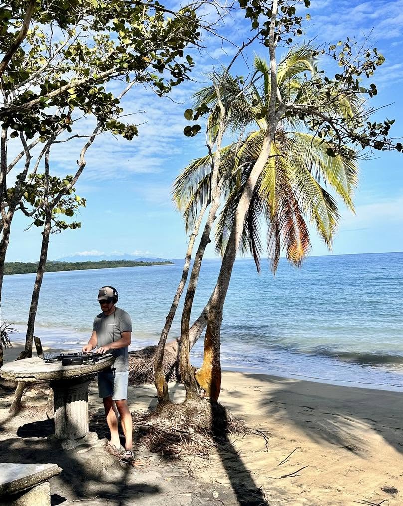 DJ Lantern DJing on a beach beside palm trees
